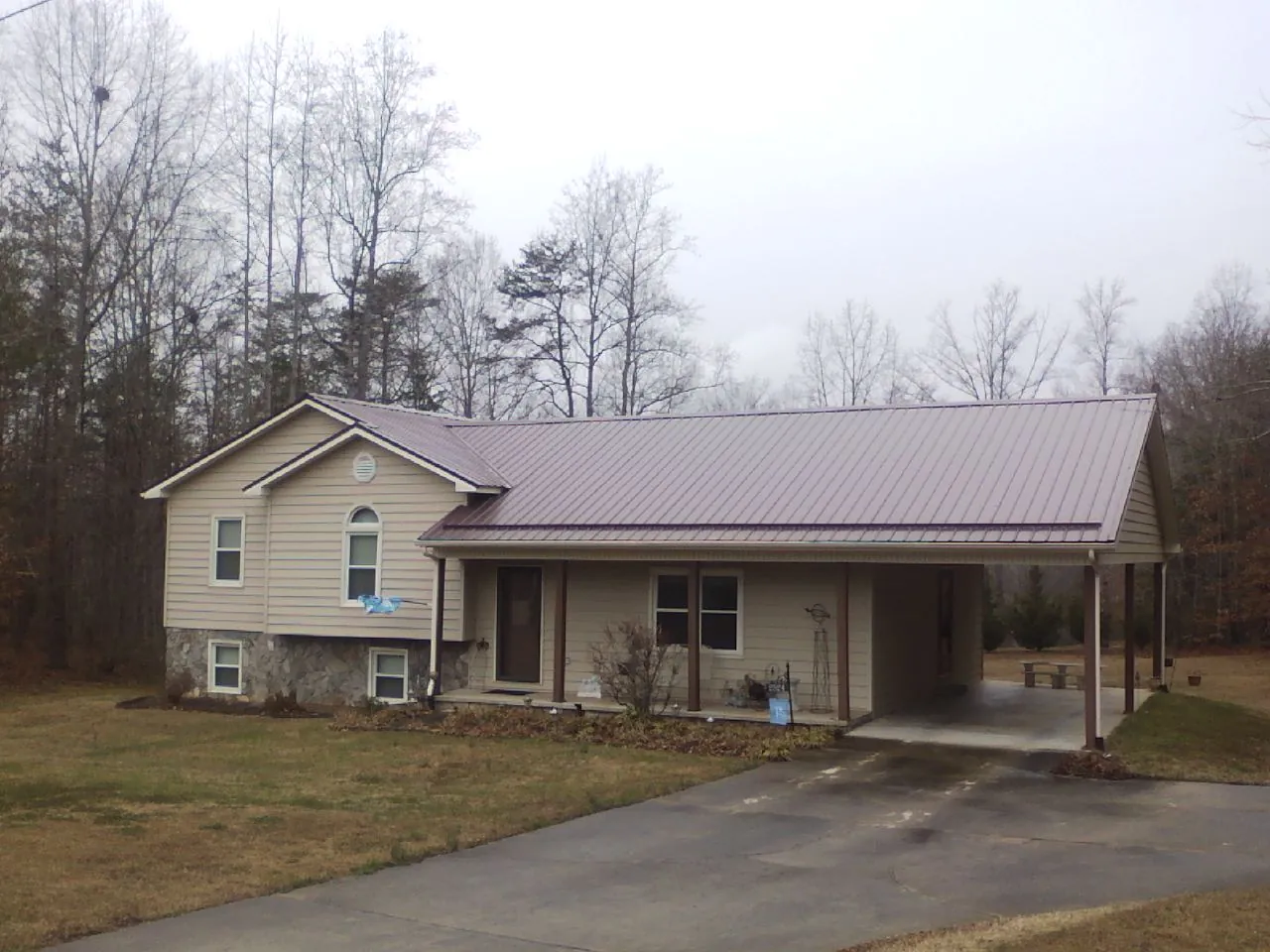Burgundy metal roof on a tan split level home with an attached carport in Ucon