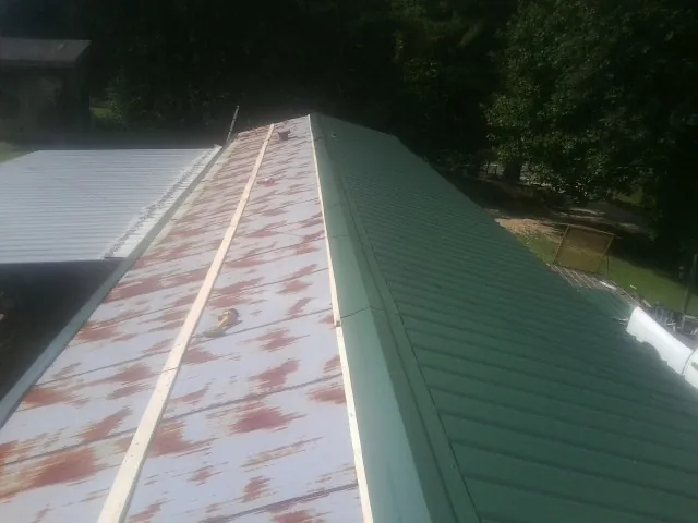 Old rusted panels beside newly installed green metal roofing — Wind Damage Roof Repair by Roofing Brothers in Ucon