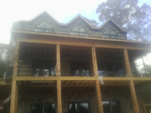 Dormers and porch framing on a large log home under construction — Roof Coating work by our crew in Ucon