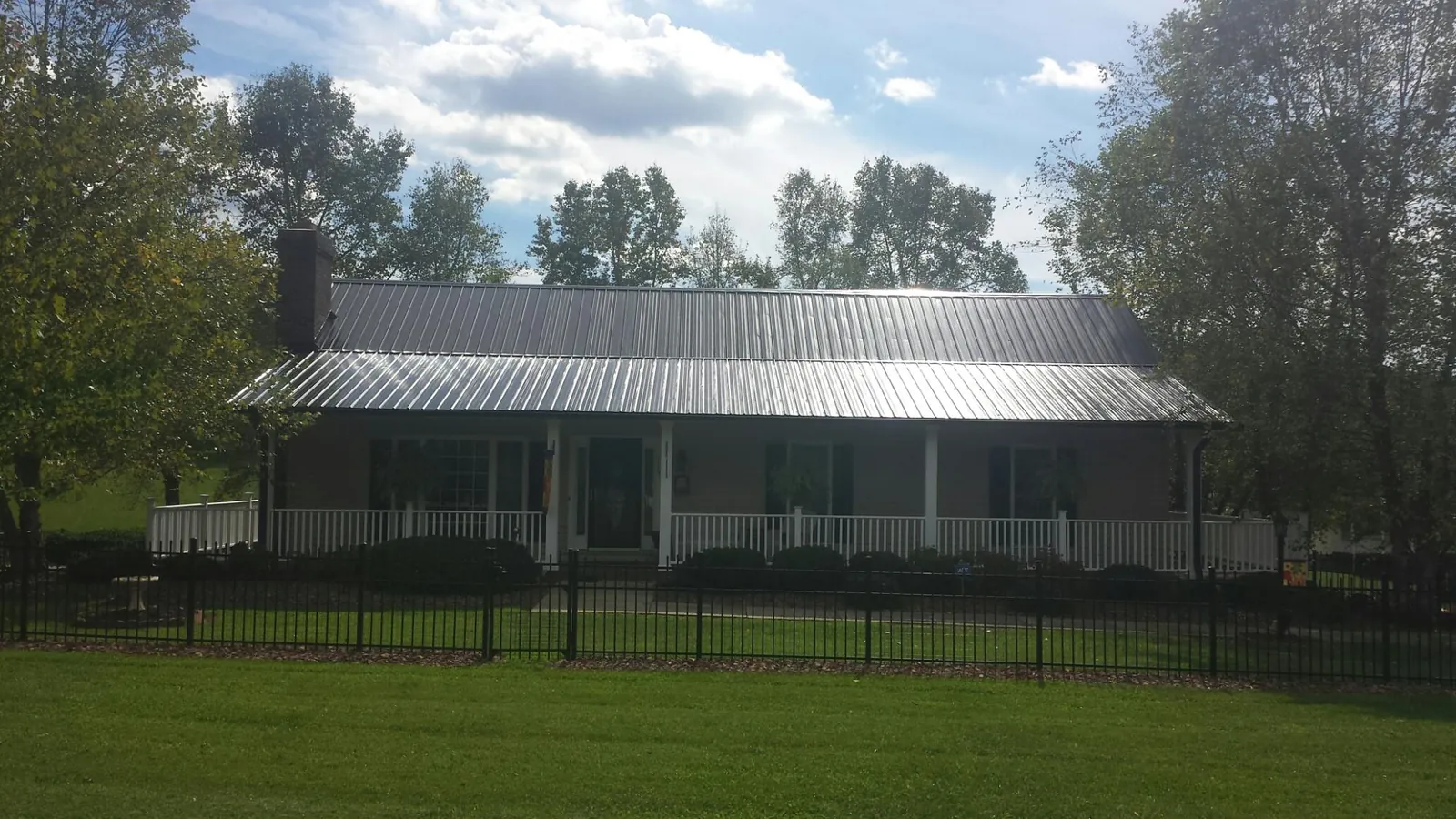 Gray metal roof on a brick ranch with a full width front porch — Gutter Guard Installation work by our crew in Ucon