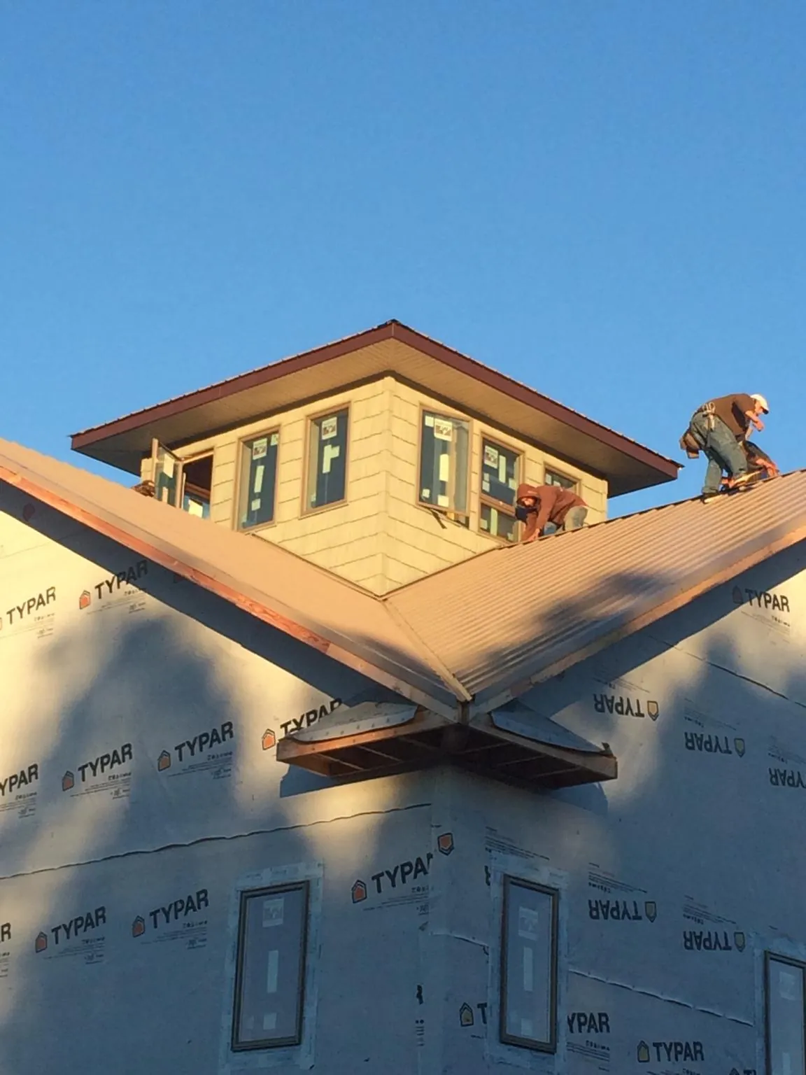 Roofers working around a rooftop cupola on a new metal roof at sunset — Roof Waterproofing in Ucon by Roofing Brothers